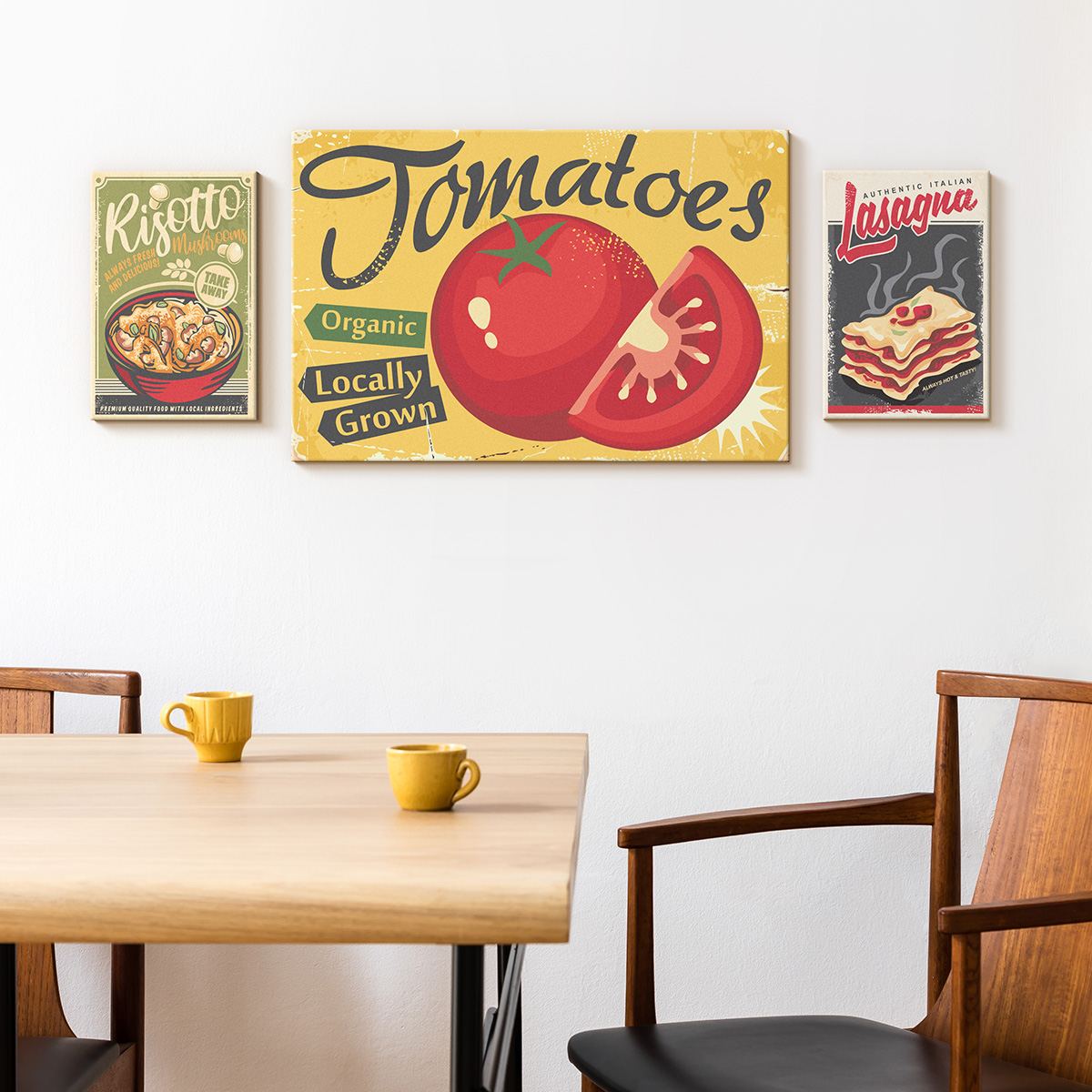Three vintage food canvases — Risotto, Tomatoes and Lasagna — above a pale oak dining table with yellow mugs.